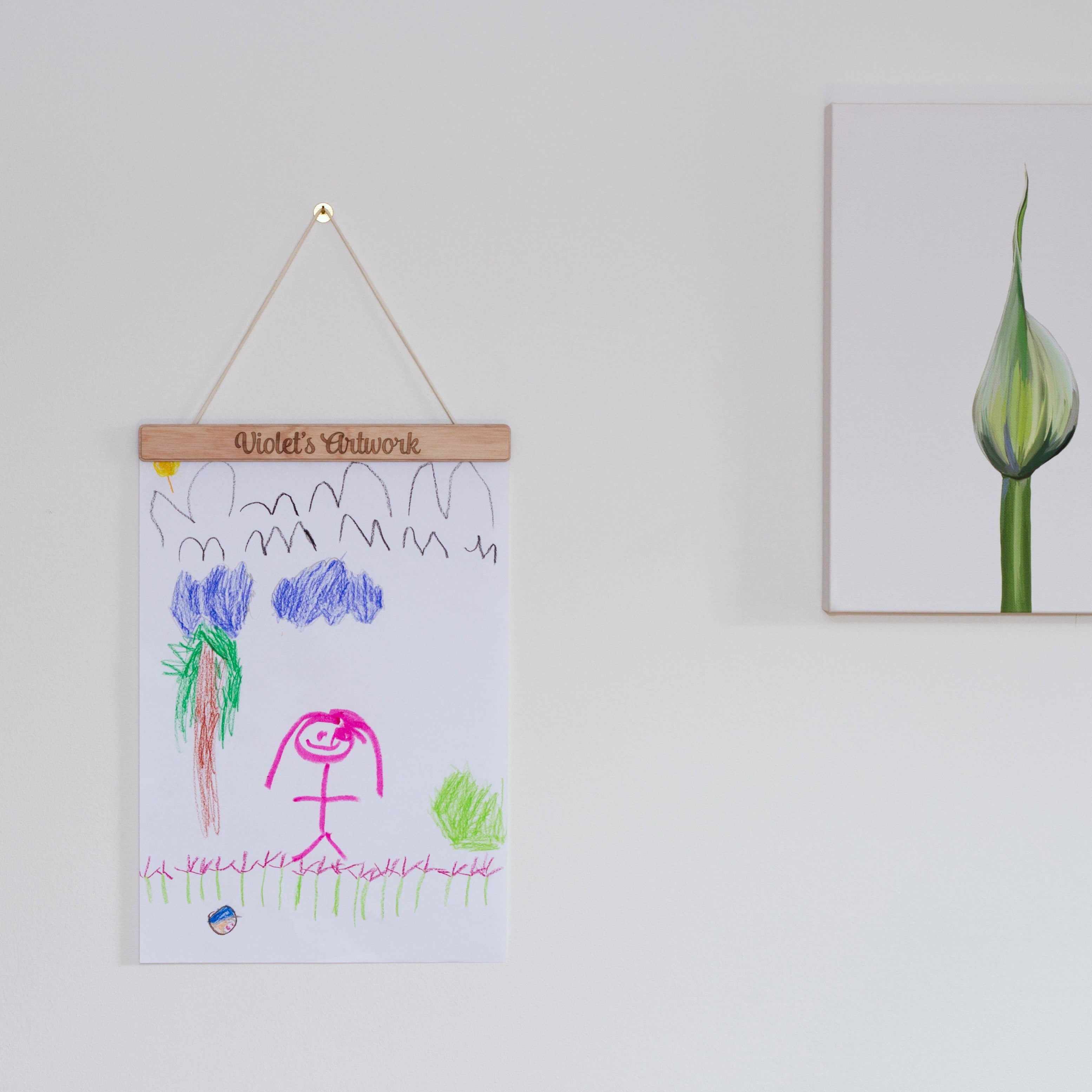 child's artwork hanging from a wooden hanger on a white wall
