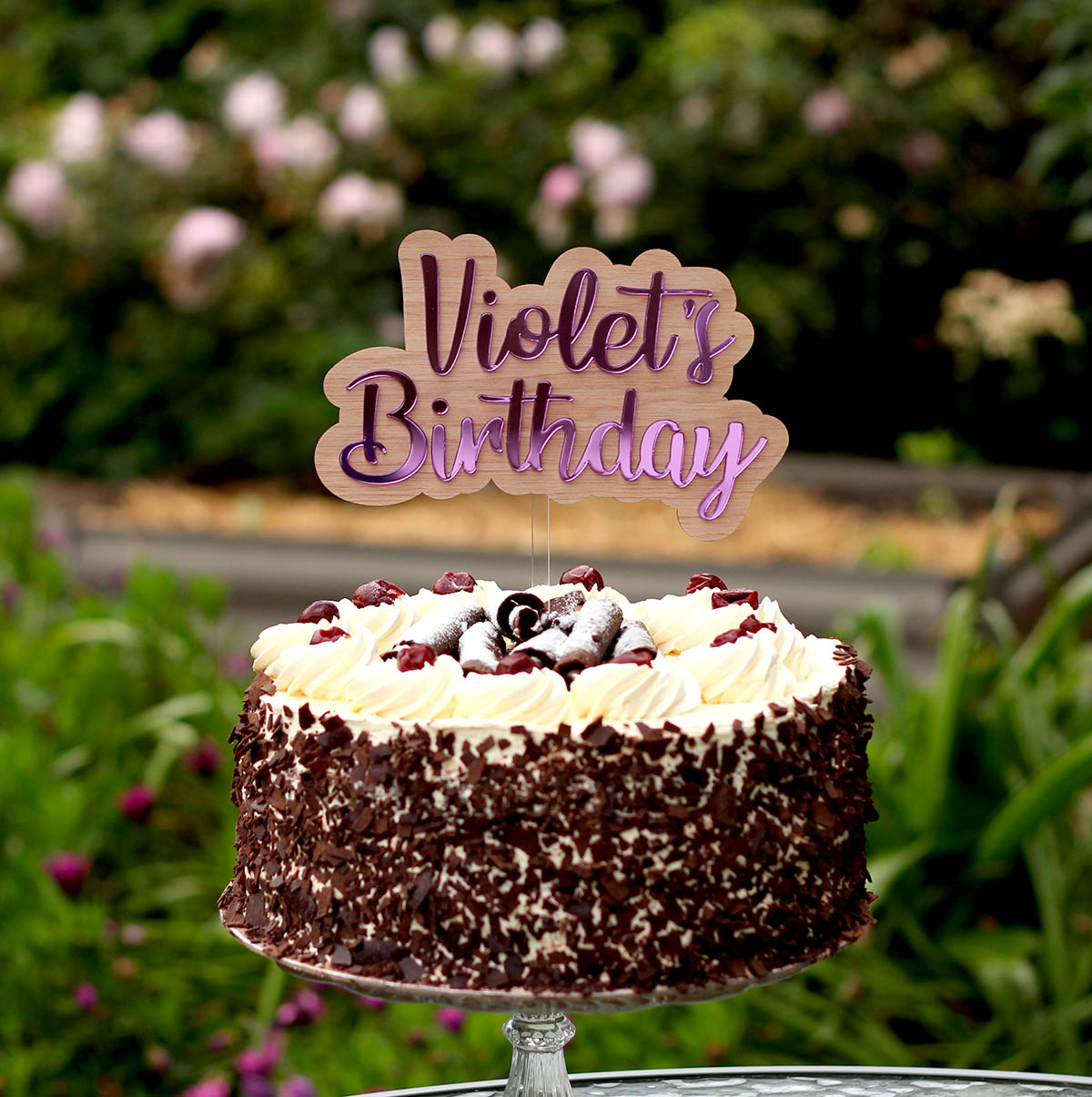 acrylic and wood cake topper in a cake that says Violet's birthday in purple mirror