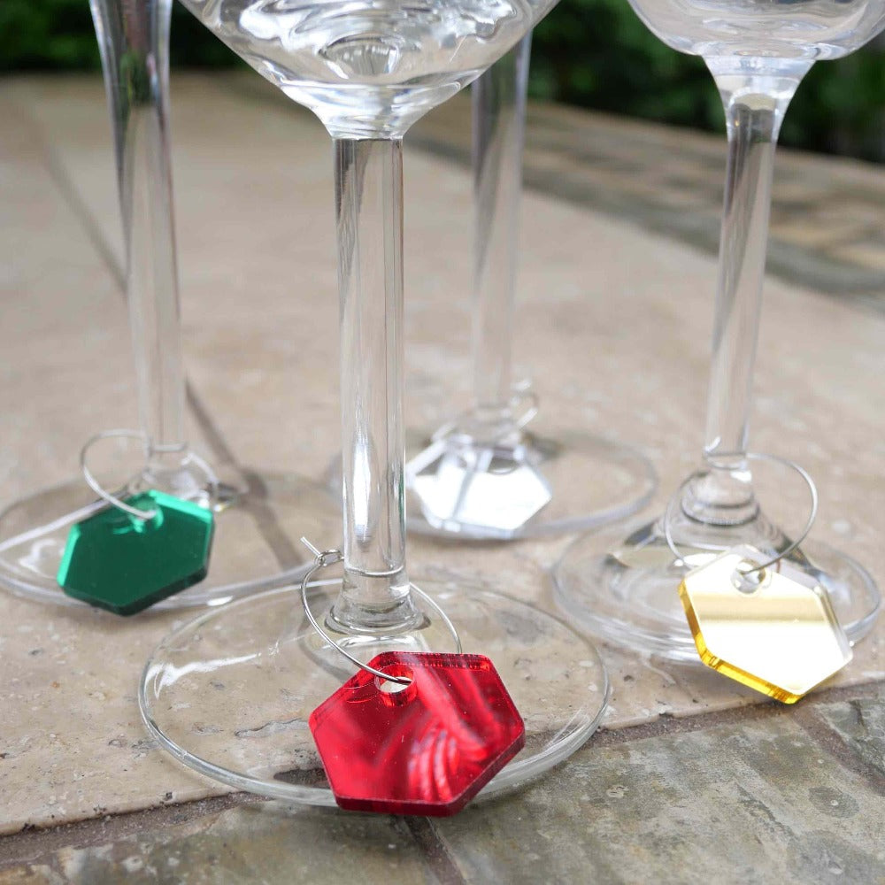 4 wine glasses with christmas coloured charms hooked around the base of the stems