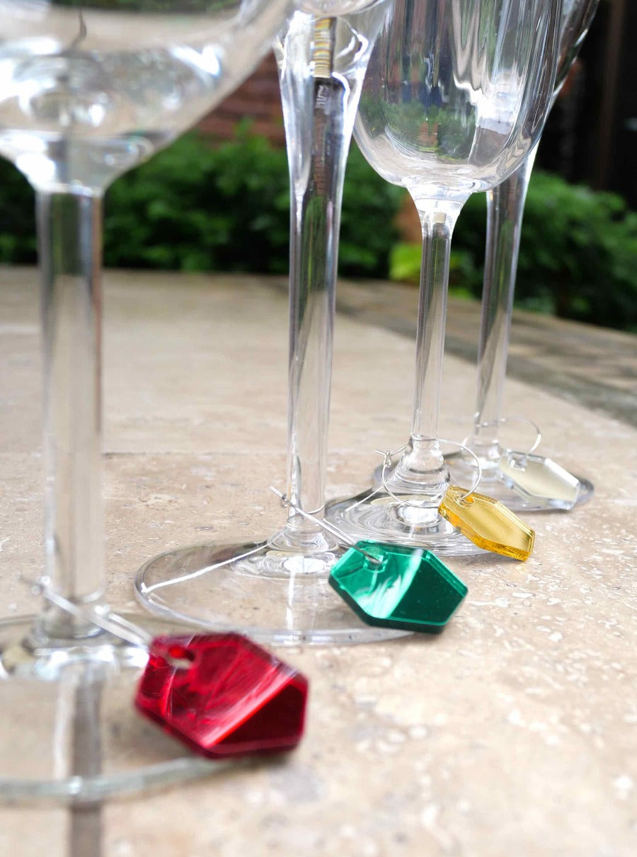 4 wine glasses with charms around the stems in christmas colours