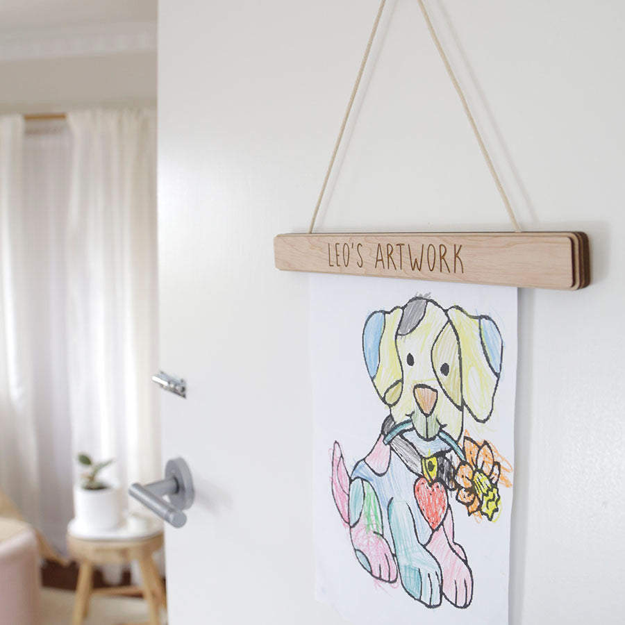 a wooden hanger with Leo's artwork etched, displaying children's drawing
