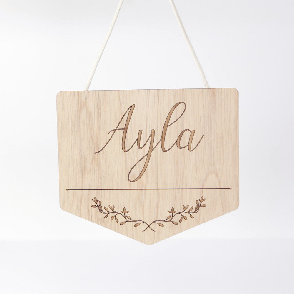 wooden sign with text "Ayla" and floral pattern underneath
