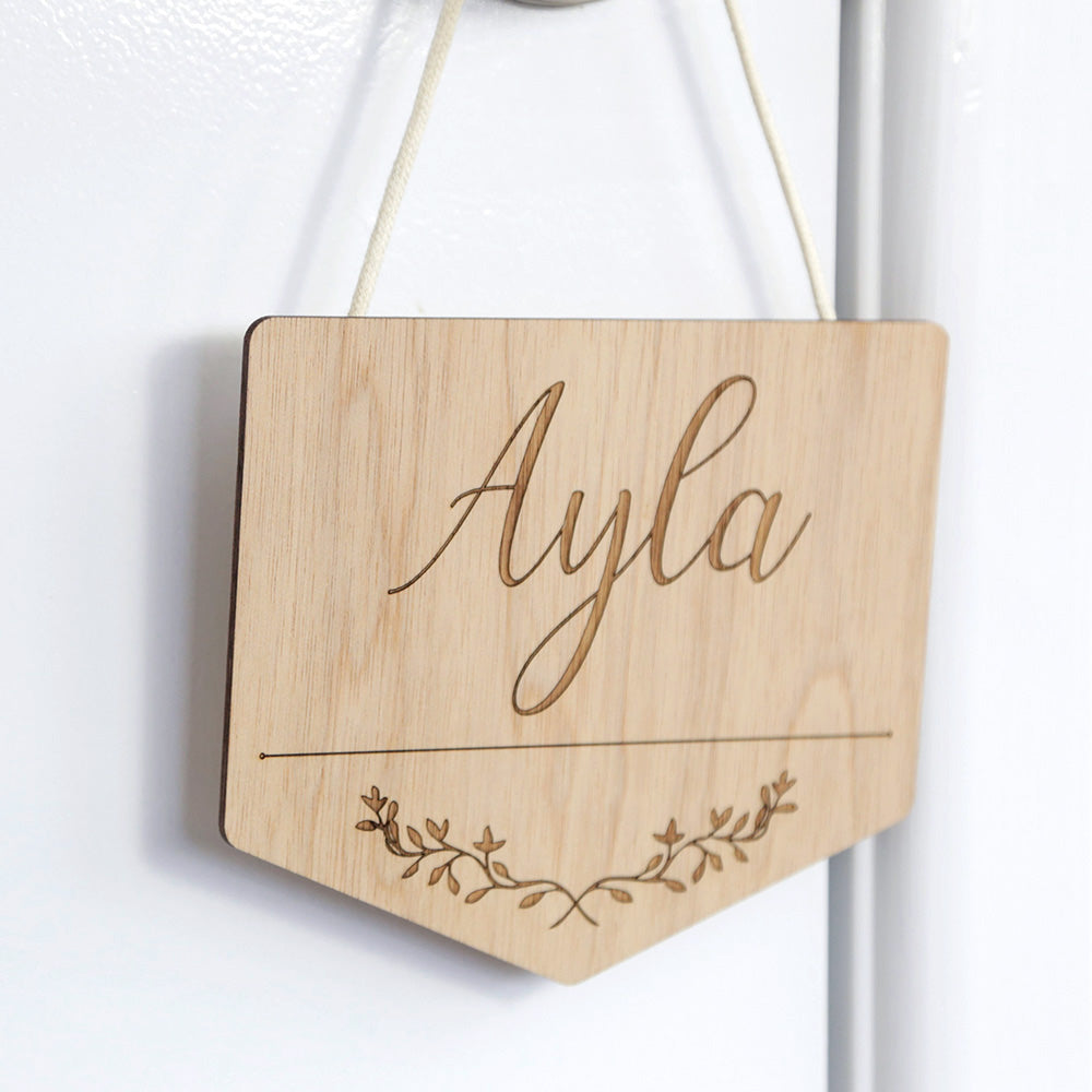 wooden door sign with text "Ayla" and floral pattern underneath